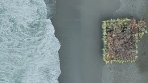 Aerial Video of Pier Casting Shadow Over Foamy Waves Crashing at Shoreline Below Stock Footage 344007803