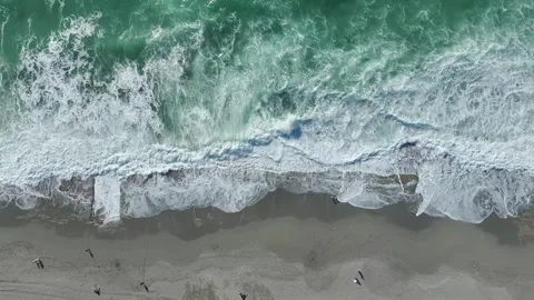 Aerial Video: Rolling storm waves leave intricate foam patterns on the sandy Stock Footage 300902437