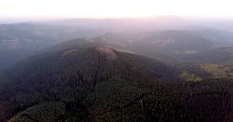 Aerial video tilting down during sunrise showing a hill and trees 動画素材 83151994