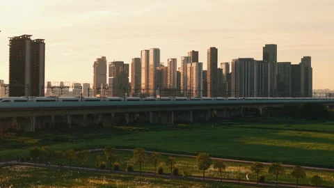 Aerial view of 2 high speed train travel on an elevated track past tall Stock Footage 340939942