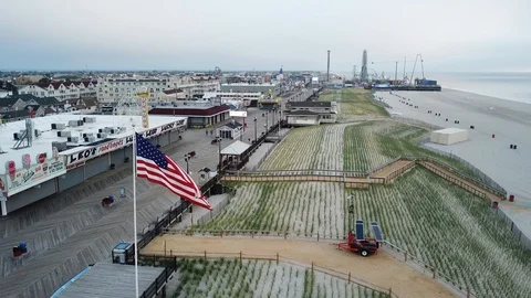 Aerial View 4K - Flag on Beach and Boardwalk, Casino Pier - Ascending Backwards Stock Footage 114450598
