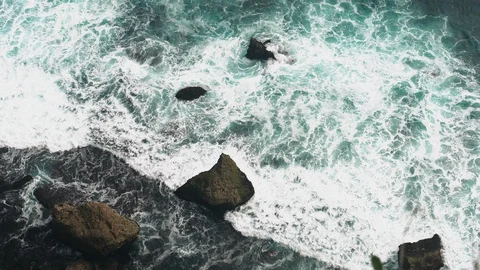 Aerial view 4k waves break on dark rocks near beach. Sea waves on the stones Video stock 119228207