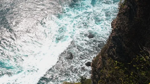 Aerial view 4k waves break on dark rocks near beach. Sea waves on the stones Stock Footage 119228444