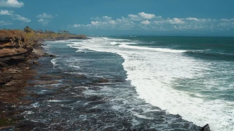 Aerial view 4k waves break on dark rocks near beach. Sea waves on the stones Stock Footage 119229094