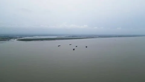 Aerial view of 5 small coaster ships waiting near an estuary, preparing to relea Stock Footage 287781620