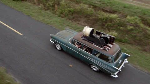 Aerial view of a 57 chevy with musical instruments on the roof Stock Footage