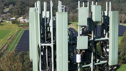 Aerial view of a 5g cell tower antenna array over a solar farm Stock Footage 341234531