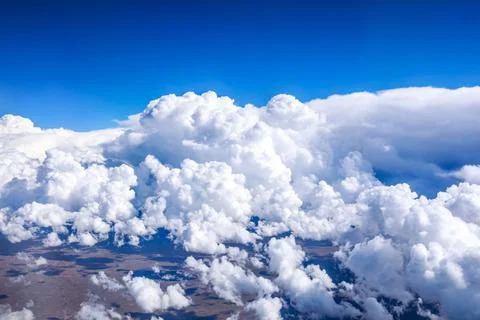 Aerial view above the clouds and mountain peaks on a sunny day. Stock Photos