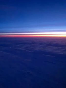 Aerial view above an extensive cloud layer at twilight with a colorful horizon t Stock-Fotos