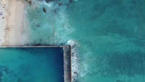 Aerial view above a small sandy beach next to a swimming pool Stock Footage 280243662