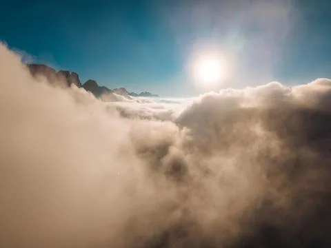 Aerial View Above Thick Clouds with Mountain Peaks and Bright Sun in Blue Sky Stock Photos