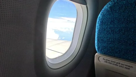 Aerial view above white clouds and wing from airplane window with blue sky. Stockbeeldmateriaal 312791753