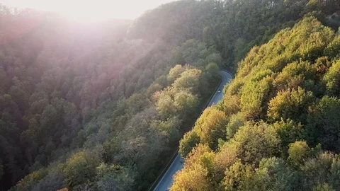 Aerial View against the sun by sunset. Car on a winding mountain road in the Stock Footage 102823684