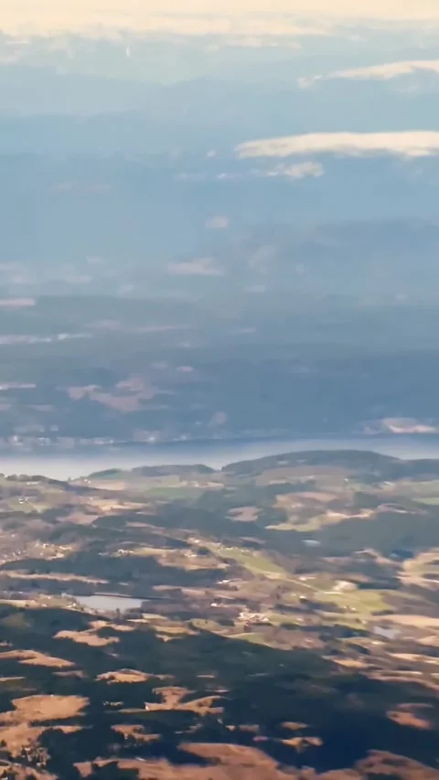 Aerial view from an airplane over patchwork countryside, lakes and hazy blue Video stock 337228943
