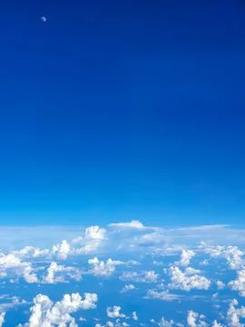 Aerial view from an airplane window featuring scattered cumulus clouds beneath a Stock Photos