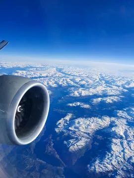 Aerial view from an airplane window featuring a jet engine above a vast snow-cov Stock Photos