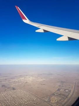 Aerial view from an airplane window featuring the aircraft wing over a vast dese Fotos de archivo