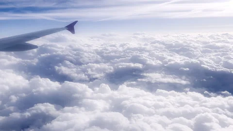 Aerial view from airplane window flying above white clouds at sunset, showing je Vidéo 337671104