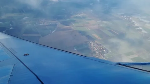 Aerial View from Airplane Window Over Patchwork Farmland Below Clouds Stock Footage 314749907