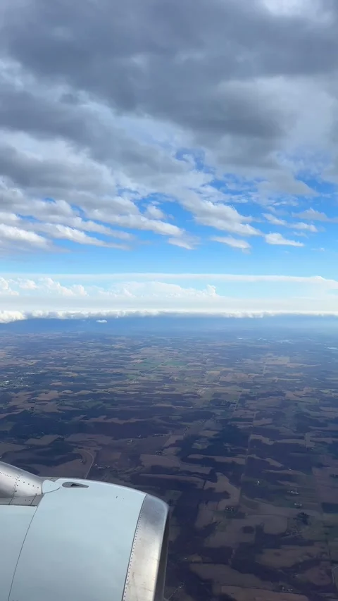 Aerial view of an airplane wing over a patchwork of fields with dramatic clouds Video stock 333806328