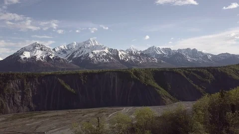Aerial view of Alaskan river cliffs with mountains in background Video stock 113533876