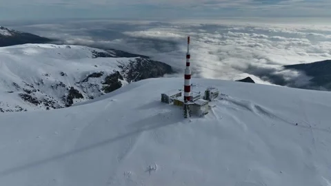 Aerial view of alpine mountain range, with snow-capped peaks and a tower Stock Footage 297992581