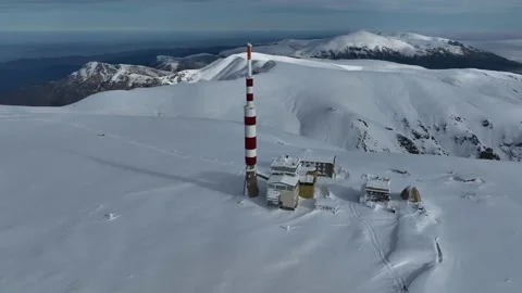 Aerial view of alpine mountain range, with snow-capped peaks and a tower Stock Footage 302956971