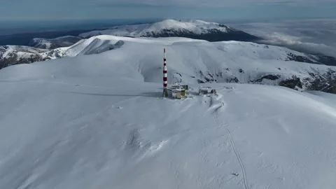Aerial view of alpine mountain range covered in snow and a communications tower Stock Footage 304089622