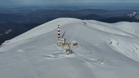 Aerial view of alpine mountain range covered in snow and a communications tower Stock Footage 319823091