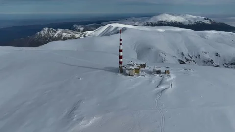 Aerial view of alpine mountain range covered in snow and a communications tower Stock Footage 321226596