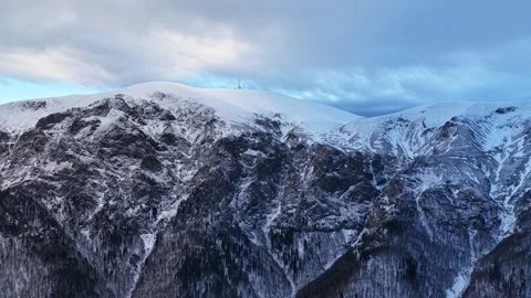 Aerial view of alpine mountain range covered in snow and a communications tower Vídeos de archivo 327863507