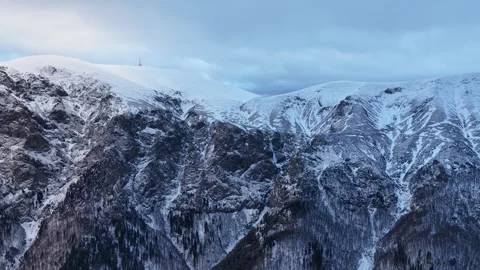 Aerial view of alpine mountain range covered in snow and a communications tower Stock Footage 328651815
