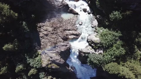 Aerial view - alpine waterfalls with a bridge over it and trekkers Stock Footage 137349371