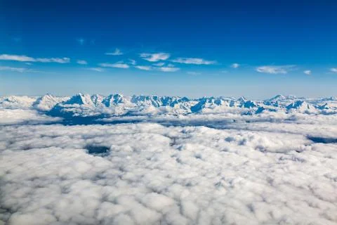 Aerial view of Alps mountain range above clouds seen from airplane over Stock Photos