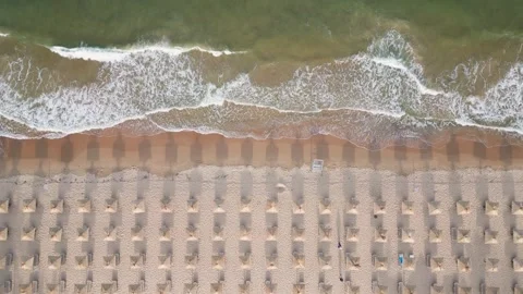 Aerial view of an amazing empty sand beach with straw beach umbrellas and Stock Footage 243380612