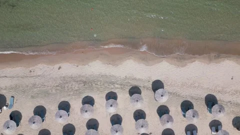 Aerial view of an amazing empty sand beach with straw beach umbrellas and Stock Footage 244236748