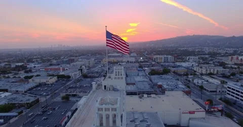Aerial view American US flag rooftop city Los Angeles cityscape at sunset 4K UHD Stock Footage