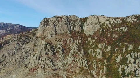 Aerial view of ancient cliffs overgrown with scarce plants in places. Sunny autu Stock Footage 151153376