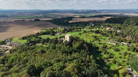 Aerial view of ancient stone tower surrounded by lush forest, patchwork fields, Stock Footage 348176208
