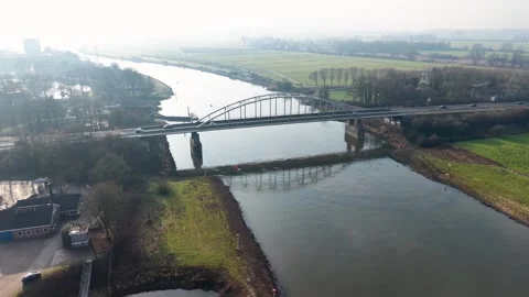 Aerial view of arched bridge over curving river in rural landscape. Vehicles Video stock 327501941