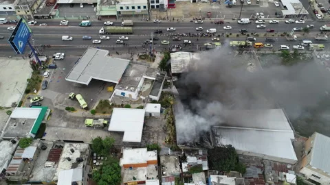 Aerial view around a building on fire, caused by a bomb, dark smoke Stock Footage 137386459