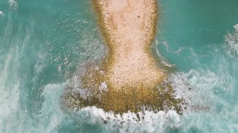 Aerial view of artificial mound in ocean and serpentine road behind it Stock Footage 67847534