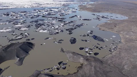 Aerial View of Ash-Covered Icebergs Floating in a Glacial Lagoon, Iceland Stock Footage 340179574