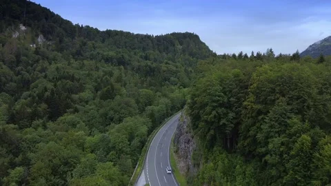 Aerial view of asphalt road between mountains covered with green forest Stock Footage 143389281