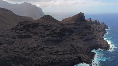 Aerial view of Atlantic waves breaking at the base of towering sea cliffs Stock Footage 346425842