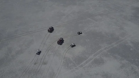 Aerial view of ATV driving down a beautiful wide open beach with crashing ocean Stock Footage 77707656