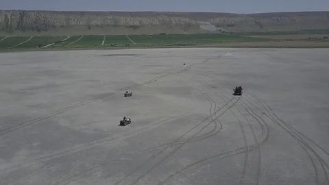 Aerial view of ATV driving down a beautiful wide open beach with crashing ocean Stock Footage 77707707