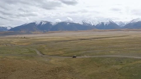 Aerial view of automobile riding along sandy road in dry mountainous valley Stock Footage 153617853