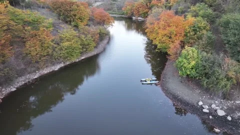 Aerial view of an autumn river surrounded by colorful trees Stock Footage 341978052