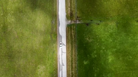 Aerial view of back road with green fields on both sides Stock Footage 156411574